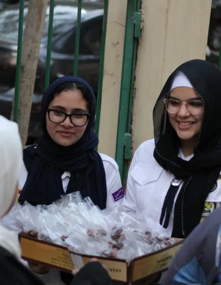 متطوعة بحجاب أبيض تبتسم وخلفها أحد الأهرامات