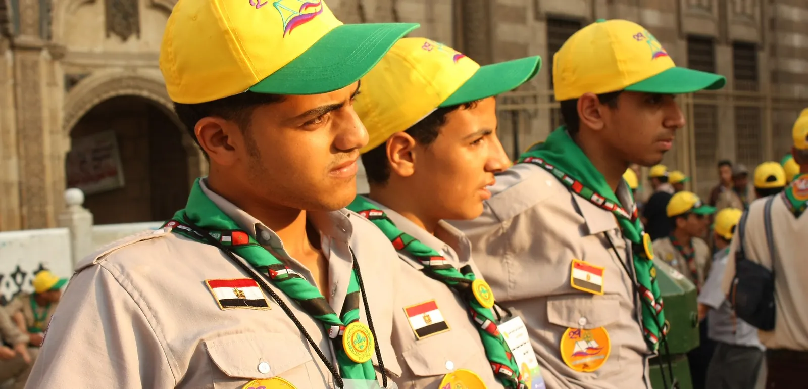 ثلاثة كشافة بالزي الرسمي يقفون في صف أثناء فعالية كشفية