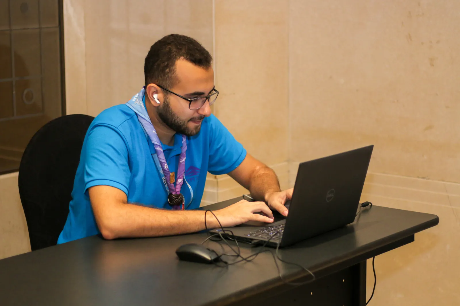 متطوع يكتب على حاسوبه المحمول على مكتب أسود مرتب