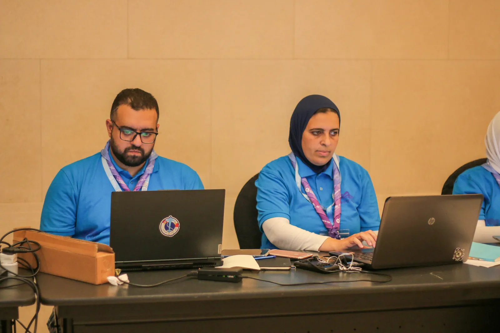 متطوعان يعملان جنباً إلى جنب على حاسوبيهما في مكتب العمليات