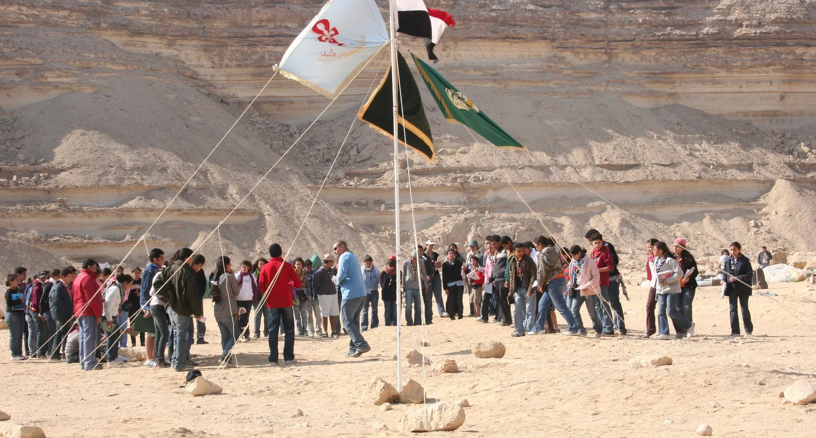 كشافة يصطفون في دائرة واسعة حول سارية العلم في الصحراء