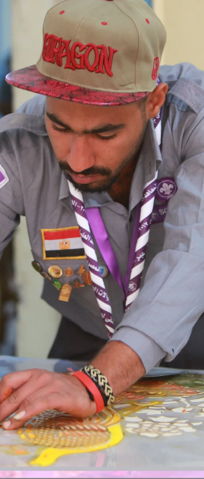 كشاف بقبعة يخط لافتة بعناية على طاولة داخلية